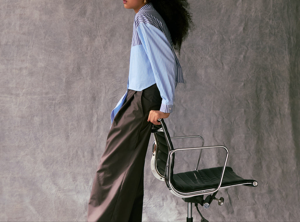 Person holding a black office chair against a gray textured wall